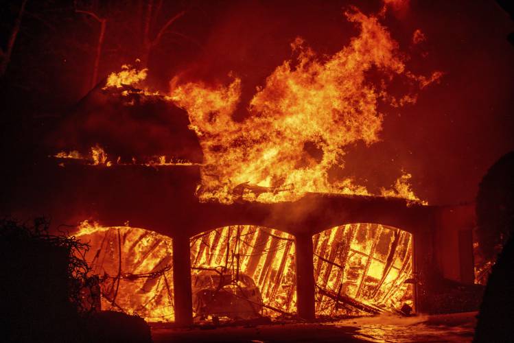 The Eaton Fire burns a residence Wednesday, Jan. 8, 2025 in Altadena, Calif. (AP Photo/Ethan Swope)