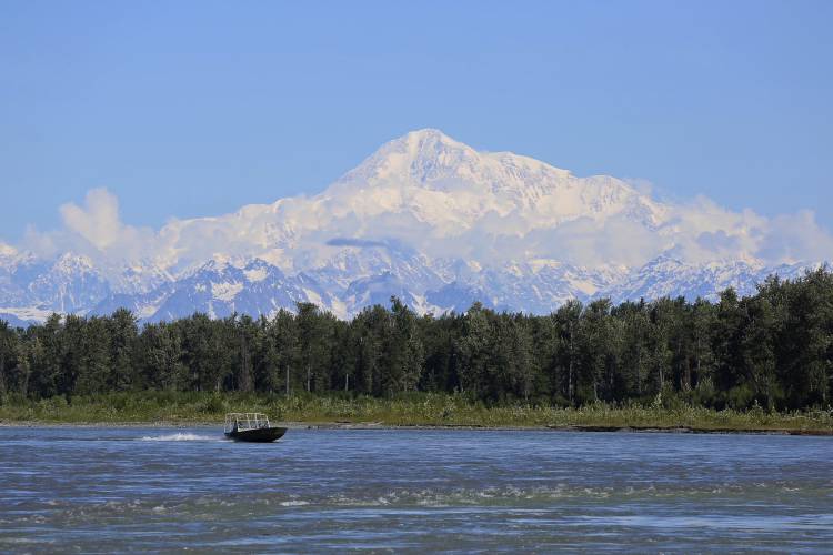 FILE - A boat is seen on the Susitna River near Talkeetna, Alaska, on Sunday, June 13, 2021, with the tallest mountain on the North American continent in the background. The U.S. Interior Department renamed the name of the landmark peak from Denali back to Mount McKinley, per an executive order from President Donald Trump. 
