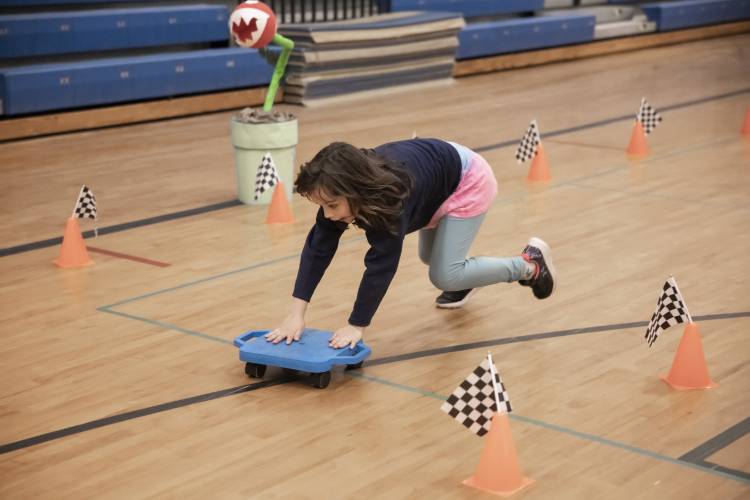 Bailey Flood, 8, races Penacook Elementary School assistant prinicipal Zach Stephenson during a Mario cart race in the school gymnasium on Thursday, March 27, 2025. The Mario Brothers-themed Escape Room included the whole school where students and their families solved mysteries in classrooms and had pizza as well.