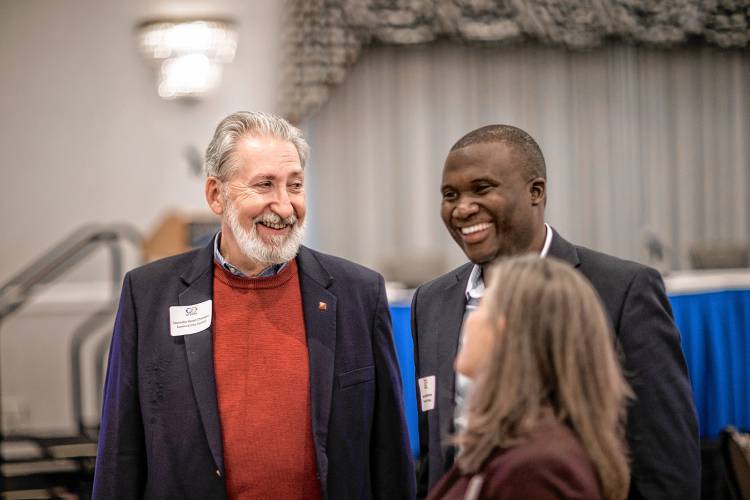Jean Hakuzimana, founder of NH Songa, (right) greets Mayor-elect Byron Champlin and Ward 5 City Councilor Stacey Brown at the Moving Together Conversations Conference at the Grappone Center on Wednesday, November 15, 2023.