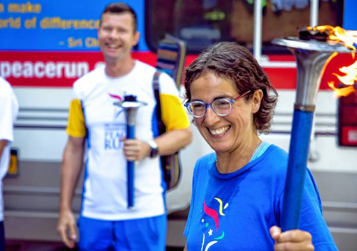 Edgars Ancans of Latvia and Nayaja Perugini of Italy get ready to exchange torches before greeting the children at the Boys and Girls Club in Concord on Tuesday, August 13, 2024, before heading to Boston on their peace run.