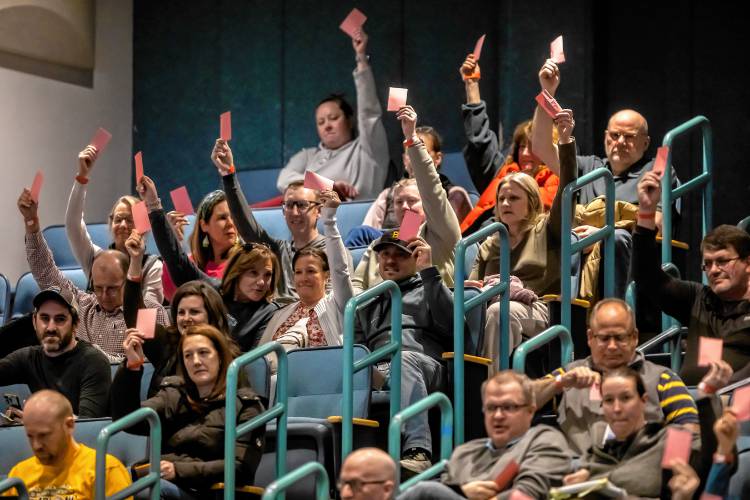 Bow residents raise their pink cards to approve article nine at the school district meeting on Friday night.