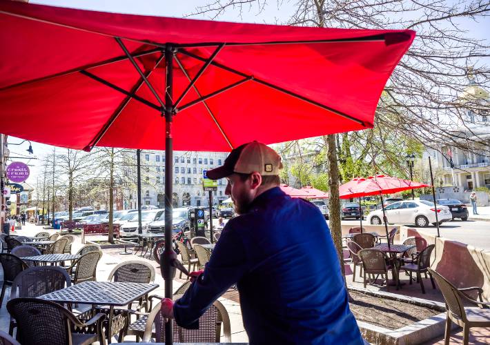 Kitchen manager Nathan Chernis of The Barley House puts up an umbrella on the first day for outdoor seating in downtown Concord. Kitchen manager Nathan Chernis of The Barley House puts up an umbrella on the first day for outdoor seating in downtown Concord.