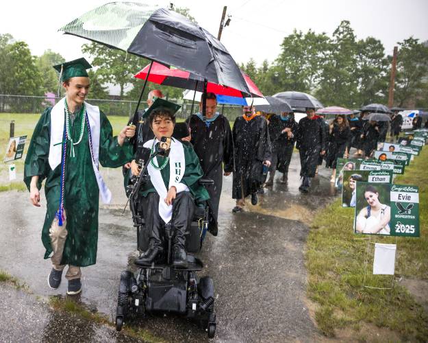 Hopkinton High classmate and friend Teddy Ehrmanntraut holds an umbrella for Constantine Salce as they make their way through the pouring rain to the 'barn' at the Hopkinton High School graduation on Friday, June, 6, 2025.