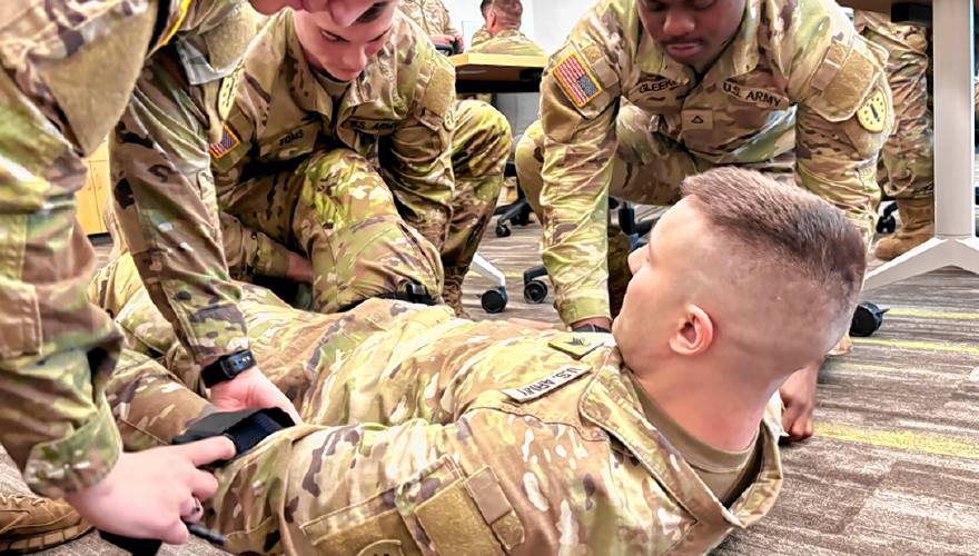 Sgt. Connor Decker plays the role of an injured soldier during training with Pfc. Macenzi Connors, Spc. Jared Toms, and Pfc. Nendoe Gleekia for their mission at the Texas border.