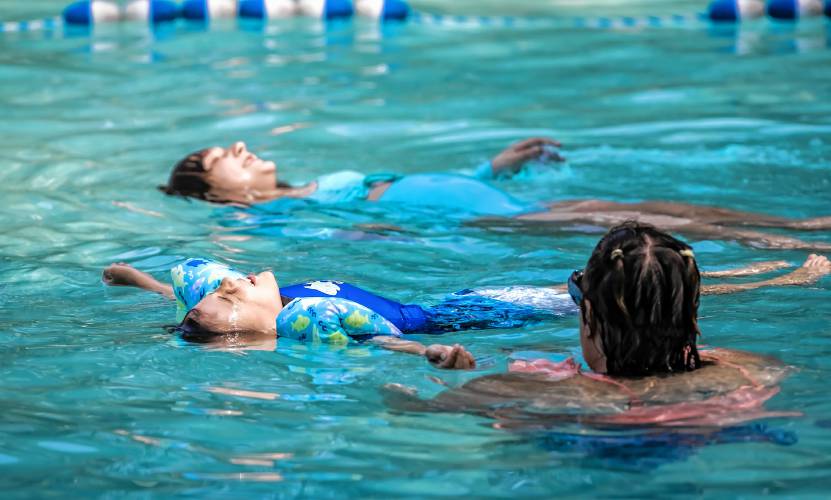 Oliver Friedman (center) and his sister Oliviya Anthony sun bath as they swim in the Garrison Pool on Monday afternoon, as their mother, Danielle Friedman looks on. The city pools are open and fully staffed for the first time in five years.