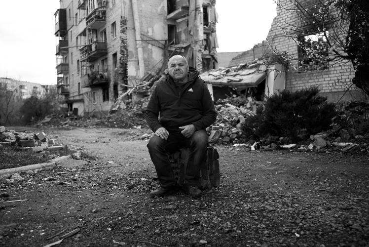 A man named Misha sits in front of his Izyum apartment where he lost his entire family in a Russian air attack.