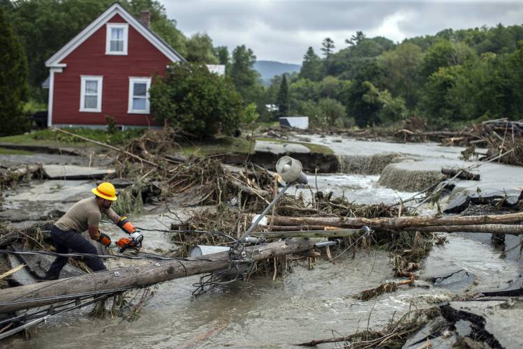 Zac Drown of Lyndon Electric Co. clears debris amid flood damage in Lyndon, Vt., on Tuesday.