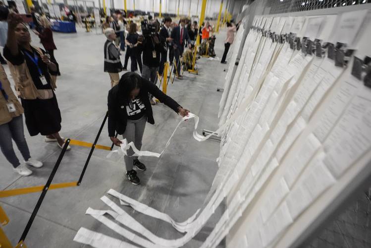 An elections staffer hangs scanner tapes used in early voting at the Fulton County Election Hub and Operation Center, Tuesday, Nov. 5, 2024, in Atlanta. (AP Photo/John Bazemore)