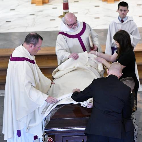 Shannon Girard puts a cloth on the casket during the service for her husband Concord firefighter, Christopher “CJ” Girard at Christ the King Parish on March 13. 
