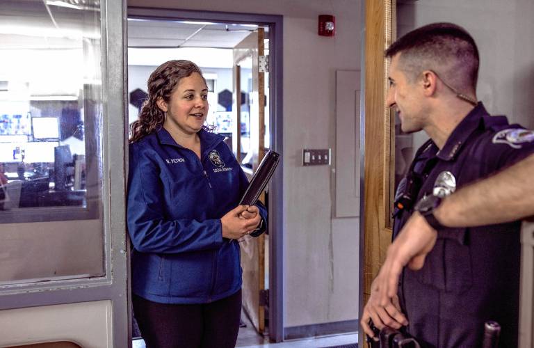Concord Police Department social worker Nicole Petrin talks with police officer Alex Cronin in the dispatch area on Friday.