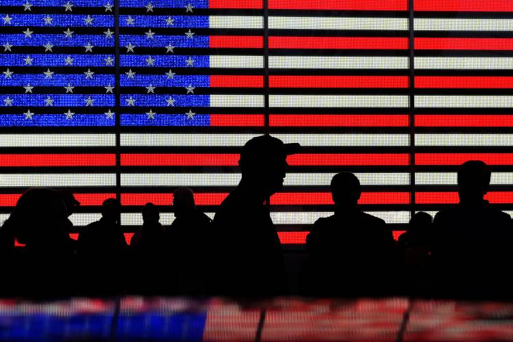 People gather near an electronic display of an American flag in Times Square in New York. People gather near an electronic display of an American flag in Times Square in New York.