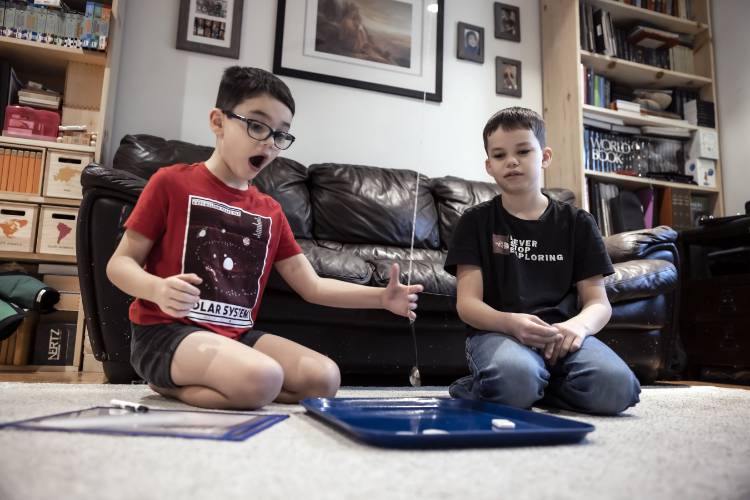  Ryan LeGeyt (right), watches his brother, Greyson as he works on an addition game in the family living room on January 9, 2025.