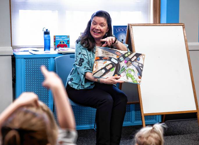 Concord reference librarian Robbin Bailey answers question as she reads to the young children upstairs at the library.