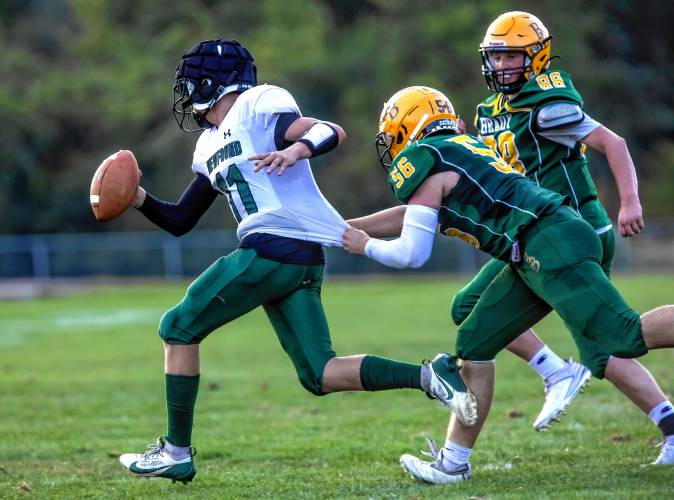 Bishop Brady lineman Jason Doyle pulls on Newfound quarterback Abe Furtado’s jersey as he chases him down during the first quarter at Memorial Field in Concord on Saturday evening.