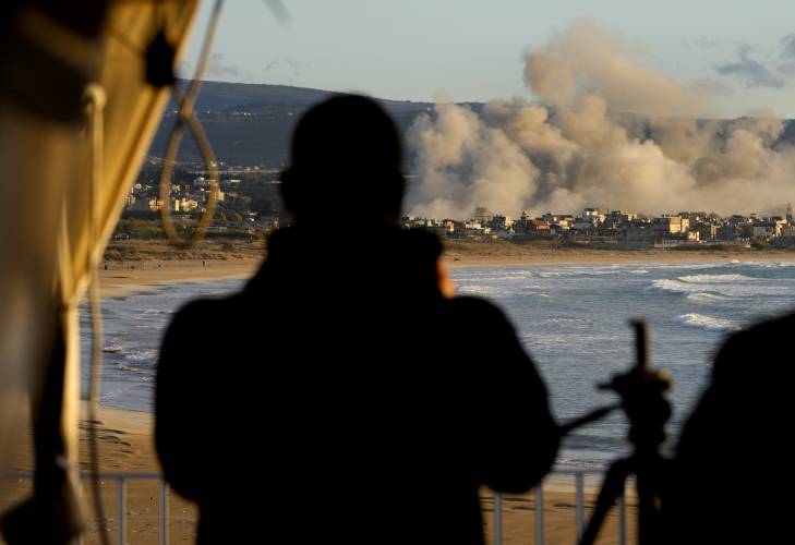 A journalist records with his mobile phone the smoke rising between buildings hit in Israeli airstrikes near the Palestinian refugee camp of Rashidiyeh, as it seen from Tyre city, south Lebanon, Tuesday, Nov. 26. A journalist records with his mobile phone the smoke rising between buildings hit in Israeli airstrikes near the Palestinian refugee camp of Rashidiyeh, as it seen from Tyre city, south Lebanon, Tuesday, Nov. 26.