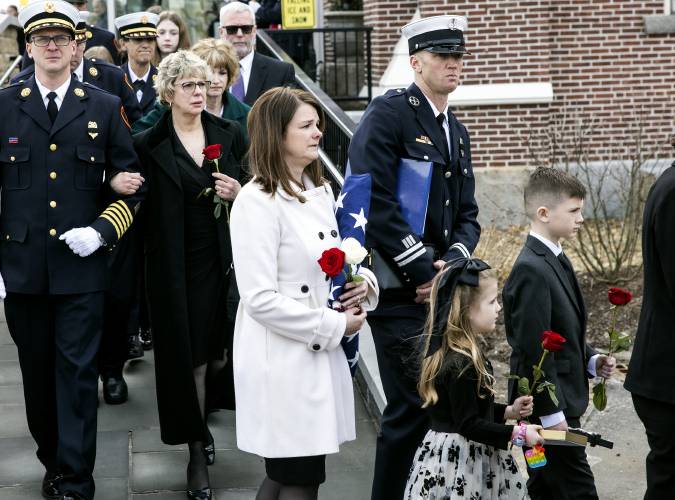 Shannon Girard leaves Christ the King Parish with her daughter, Camille, and her son, Greyson, all holding flowers after the service for Concord firefighter, CJ Girard at Christ the King Parish on Thursday. 