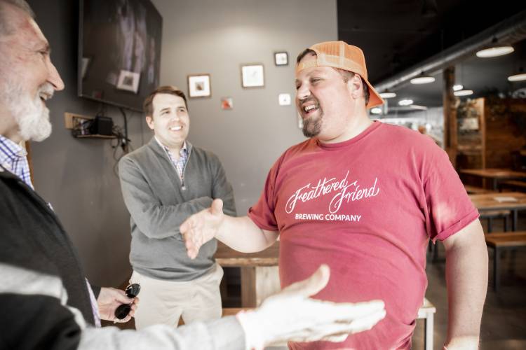 Tucker Jadczak, owner of Feathered Friend Brewing Co., greets Concord Mayor Byron Champlin as U.S. Representative Chris Pappas looks on after they entered the brewery to talk about the tariff situation Jadczak has experienced.