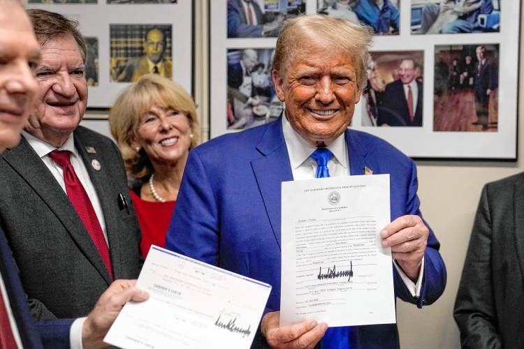  Donald Trump holds paperwork  as he signs up to be on the 2024 Republican presidential primary ballot at the State House.