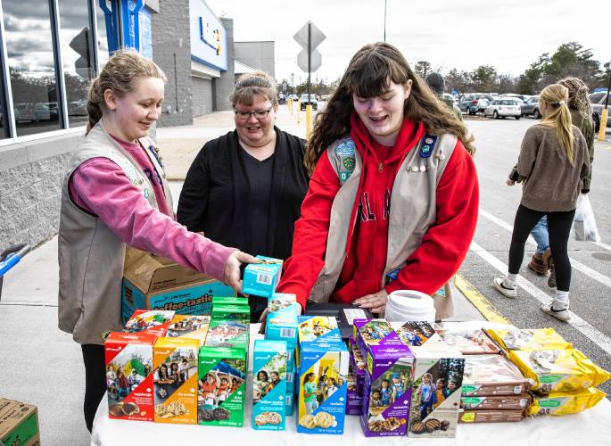Stacy Duffy, center, watches as daughter, Madison, left, and Cynthia Pelletier set up the cookie table in front of Walmart on Sunday.