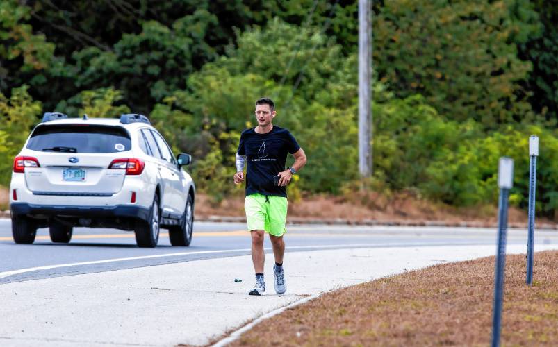 Matty Gregg runs along the Daniel Webster Highway in Merrimack on Thursday. Gregg is running the length of the state for child hunger.