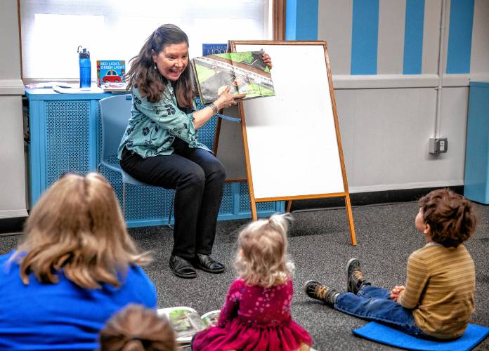 Concord reference librarian Robbin Bailey answers question as she reads to the young children upstairs at the library.