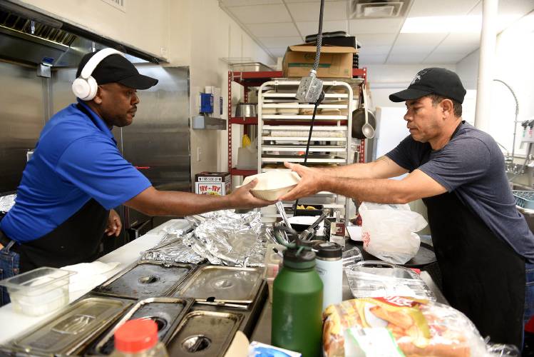 Restaurant workers Jean Alain Charles, left, and Germain Pierre work on an order at The Karibbean in West Lebanon. Both men are originally from Haiti. The restaurant makes Caribbean and Haitian food.