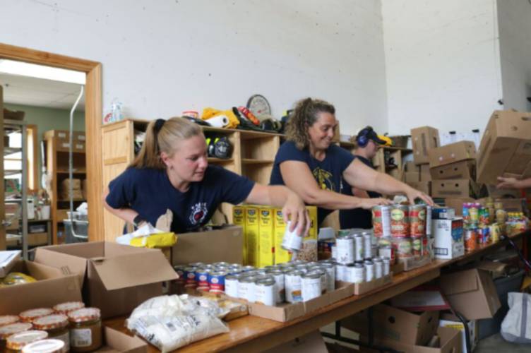 The Errol food pantry coordinator, Sara Dionne, and one of the pantry's founders, Christy Langlois, arrange cans of food for clients. Langlois works for the New Hampshire Food Bank, overseeing its work in Coos and Grafton Counties.