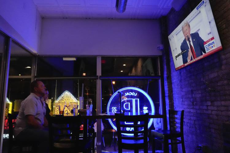 A couple watches former President Donald Trump speak on television on July 18 in Milwaukee.