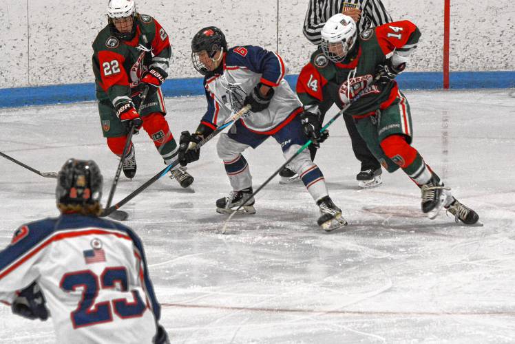Belmont-Gilford’s Evan Guerin (center) maintains possession of the puck while Pembroke-Campbell’s Thomas Hanson (14) defends during Saturday’s game at Merrill Fay Arena in Laconia. Guerin assisted on the game-winning goal in Belmont-Gilford’s 2-1 win.