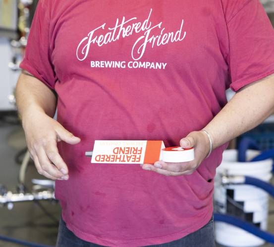 Tucker Jadczak, owner of Feathered Friend Brewing Co., holds  the beer tap handle that he ordered from Canada where he received a $750 tariff bill last week.
