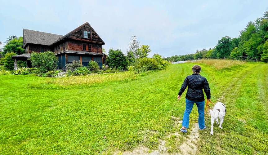 Sue Chollet walking one of her dogs, Rosie, around the farm road at Nubanusit Neighborhood. 