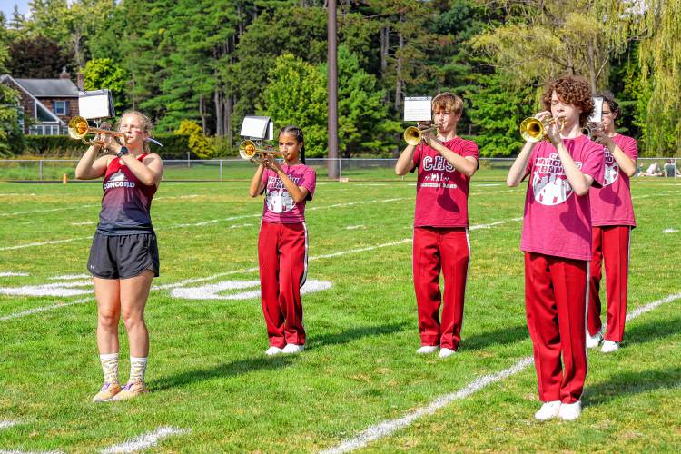 Phoebe Dater-Roberts (left) plays the trumpet at a football half-time performance after competing in a cross-country event