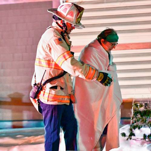 Concord fire chief John Chisolm helps a resident get out of the Granite Ledges on Friday night after a two-alarm fire hit the facility across from Concord Hospital.