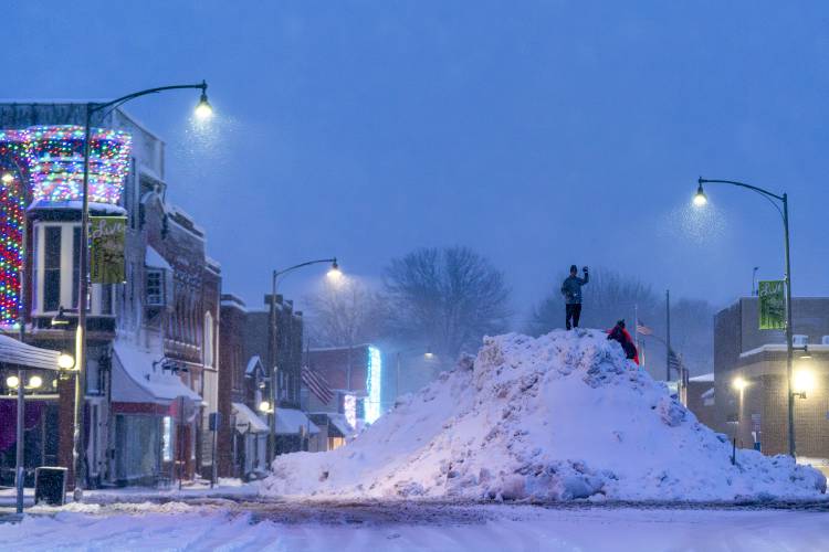 People play on an large snow pile in Oskaloosa, Iowa, Tuesday, Jan. 9, 2024. (AP Photo/Andrew Harnik)