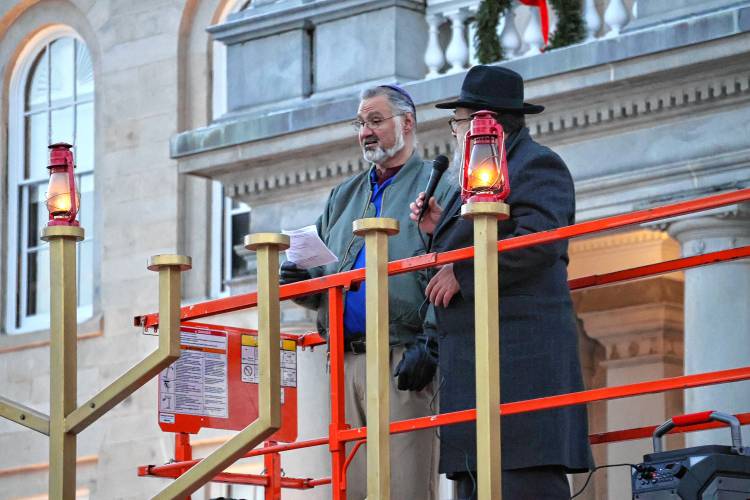 Rabbi Levi Krinsky, regional director of Chabad of New Hampshire and Scott Plaut of Nashua, kindle the 13-foot Menorah in front of the State House marking the first night of Hanukkah. Hanukkah is celebrated for eight days with an additional candle lit each night.