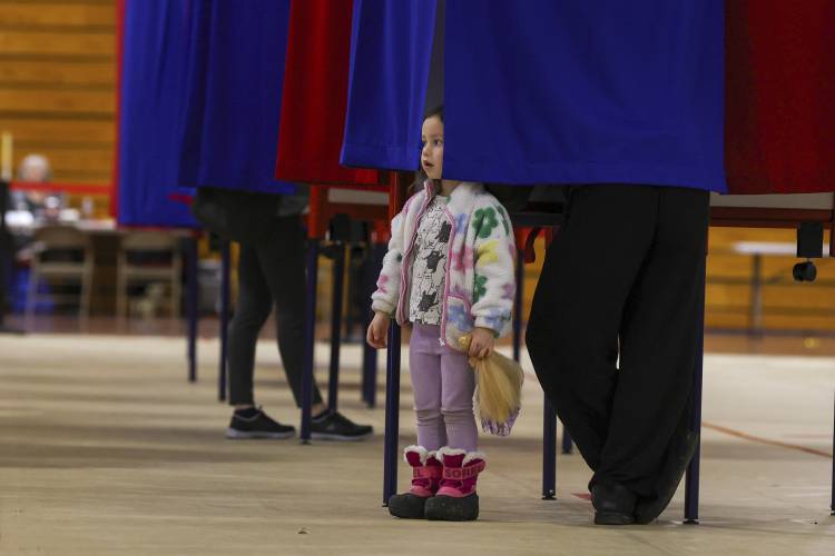 Elodie McCarran, 3, peaks out from a curtain as mother Lauren votes in Derry, N.H., on March 11.