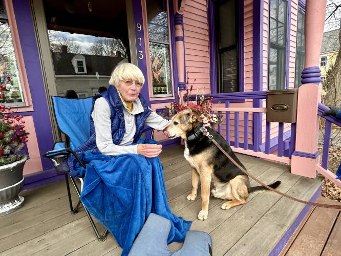 Barbara Filion enjoys a quiet morning on her front porch in Portsmouth with her neighbor's dog Buddy.