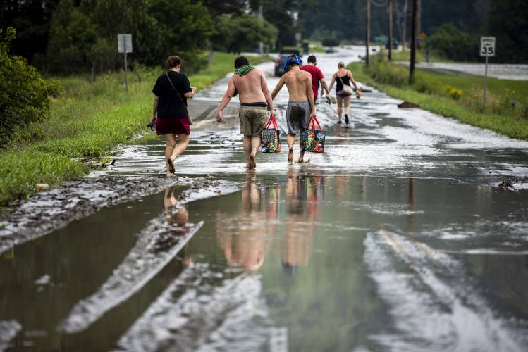 Residents walk barefoot away from flood damage in Lyndon, Vt., Tuesday, July 30, 2024. (AP Photo/Dmitry Belyakov)