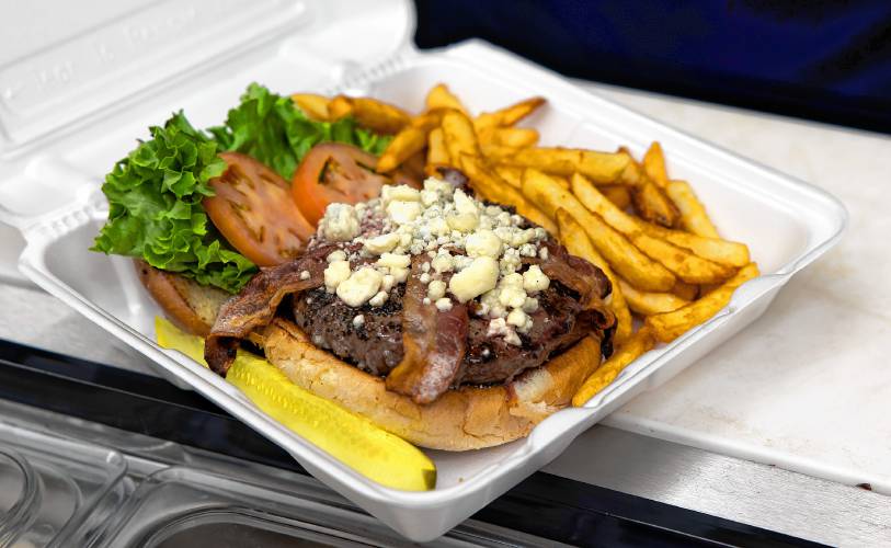 Scott Partridge prepares a blue cheese bacon burger with fries to go at the Friendly Diner in Pittsfield.