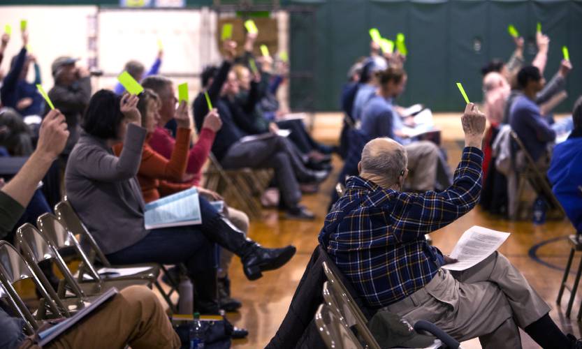 Henniker residents hold up green cards to pass warrant article 19 at the town meeting held at Henniker Community School on Saturday, March 18, 2023. Henniker residents hold up green cards to pass warrant article 19 at the town meeting held at Henniker Community School on Saturday, March 18, 2023.