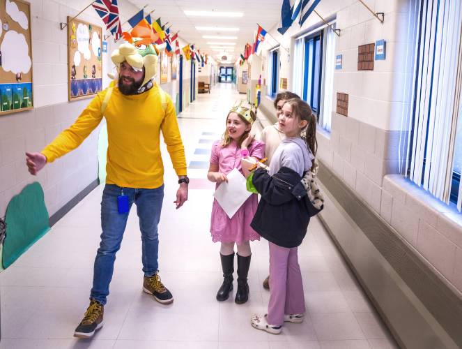 Sophie Kliener, 9, and sisters Alice and Molly Rudis greet “Bowser,” a.k.a. Penacook Elementary School assistant principal Zach Stephenson in the hallway of the school during the Mario Brothers-themed Escape Room night at the school on Thursday evening.