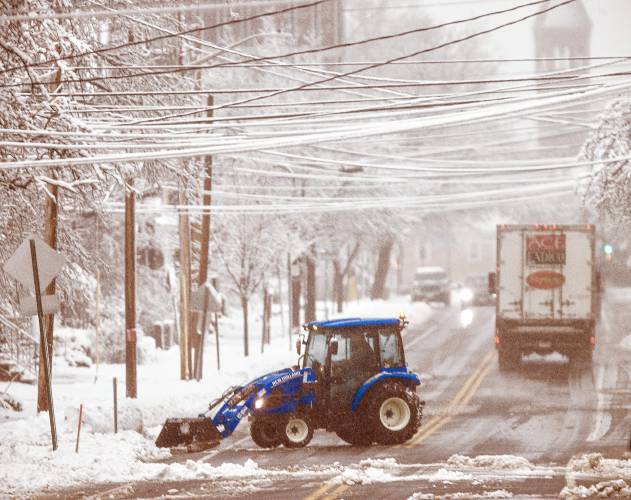 A tractor clears a driveway off of South Street in Concord on Thursday morning, April 4, 2024.