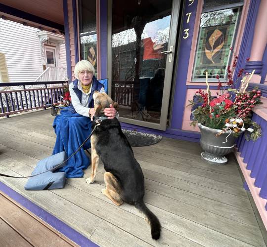 Barbara Filion enjoys a quiet morning on her front porch in Portsmouth with her neighbor's dog Buddy.