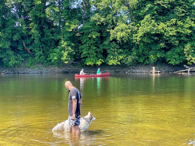 Dexter and his owner, Nathan Lamere of Penacook cool off at Riverland Beach in Canterbury on Tuesday during the start of the region's heat wave.