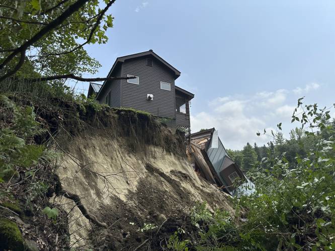 A damaged house sits on a ledge after flooding in Lyndonville, Vt., Tuesday, July 30, 2024. (AP Photo/Nick Perry)