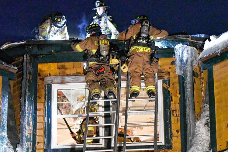Concord firefighters works on the roof of Granite Ledges for a fire on Friday night, February 14, 2025. The two-alarm fire forced residents out into the streets and then to be evacuated to Concord Hospital across the street.
