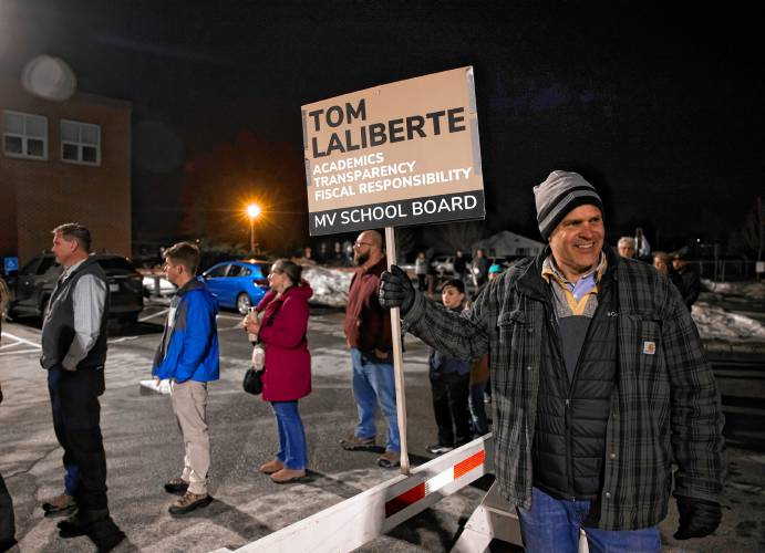 Tom Laliberte holds his sign outside in the parking lot of Merrimack Valley High School as residents wait in line to vote at the school district meeting on Thursday night, March 6, 2025.