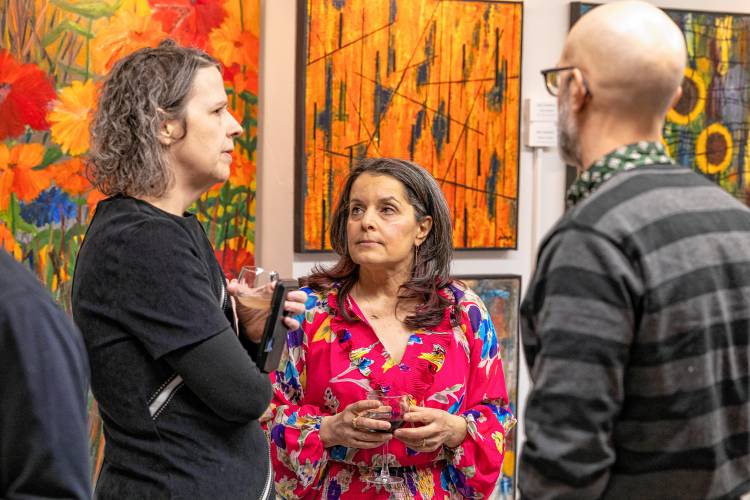 Local painter Erica Bodewell, center, speaks with guests at an opening.
