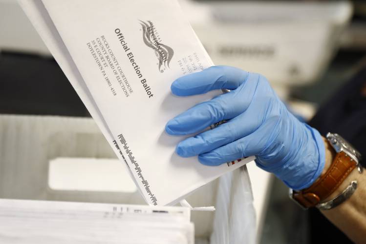 In this May 27, 2020 file photo, a worker processes mail-in ballots at the Bucks County Board of Elections office prior to the primary election in Doylestown, Pa.